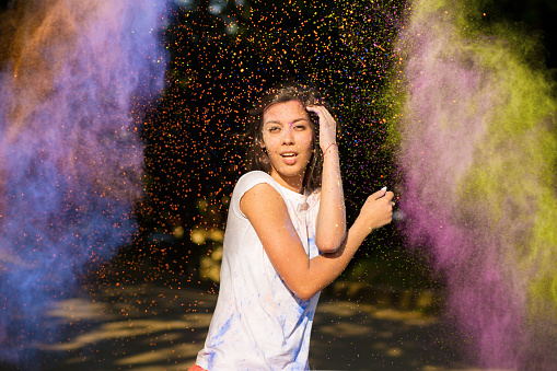 Pretty young asian woman with long hair playing with Holi powder