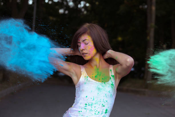 istock Lovely brunette woman with short hair posing with exploding Holi blue and green paint 1328462788