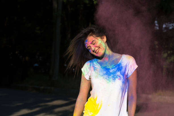 istock Positive brunette girl posing with exploding Gulal powder in the park 1328462964