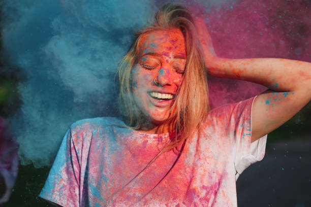 istock Pleased blonde girl having fun with exploding blue and pink dry powder celebrating Holi festival 1328463053