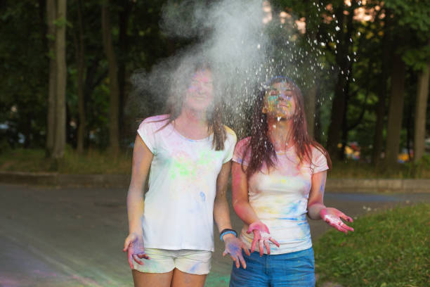 Two smiling friends having fun with Holi powder in the park