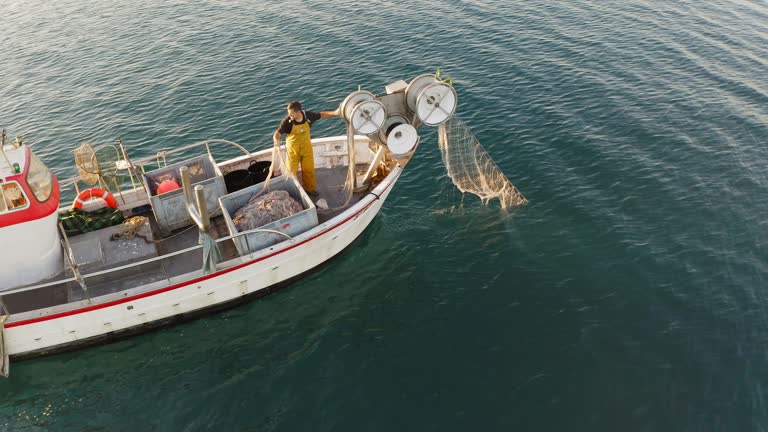 Mid Adult Fisherman Reeling in Trawl Net