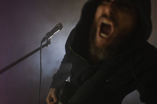 Heavy metal rock singer screaming in a live show with stage lights