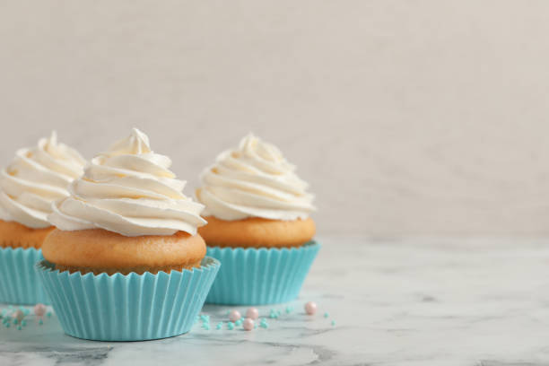 istock Delicious cupcakes decorated with cream on white marble table, space for text 1328469371