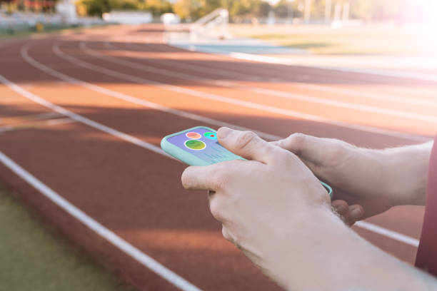 istock hands holding a smartphone with sports app, on running track 1328470670