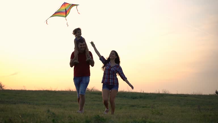 Family playing with kite on meadow