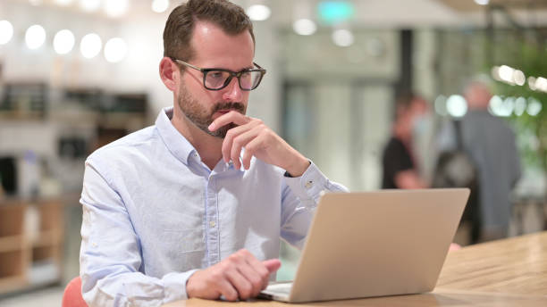 istock Pensive Businessman Thinking and Working on Laptop in Office 1328471699
