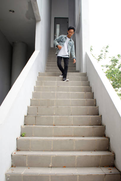 young adult man walking downstairs, wearing a denim jacket and shirt