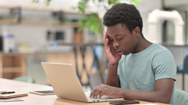 istock Stressed Young African Man with Laptop having Headache 1328473300