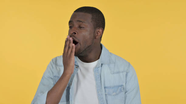 istock Sleepy Young African Man Yawning, Yellow Background 1328476659
