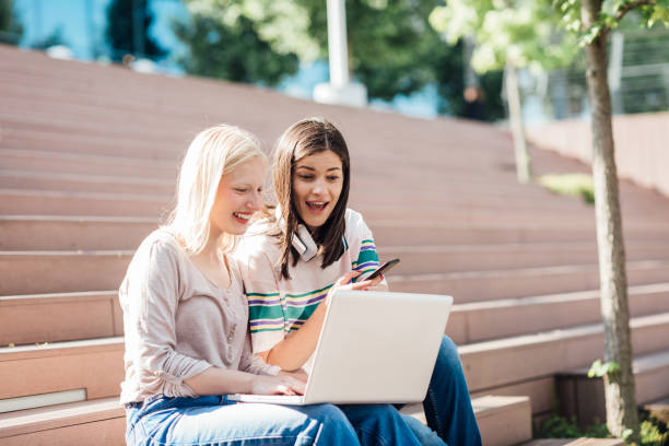 istock Two girls using laptop and having fun online 1328478359