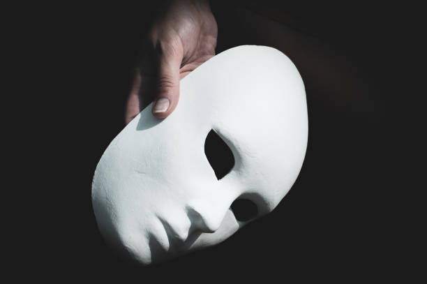 istock Hand holding blank unpainted Columbine mask. Anonymous concept 1328478955