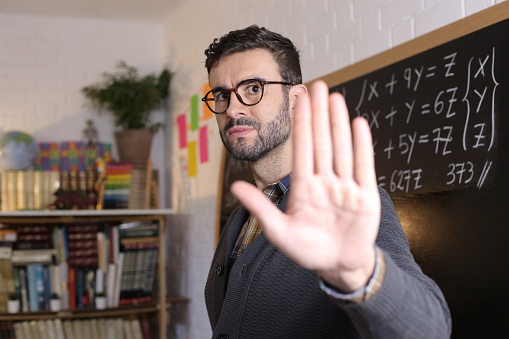 Male teacher showing stop sign with hand gesture.