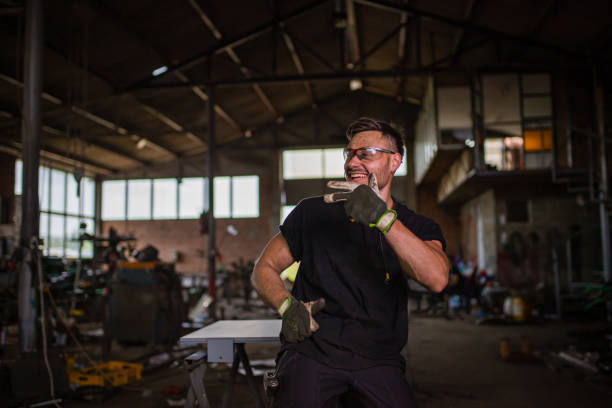 Portrait of a cheerful young engineer and metal worker, having a good time at the metal factory after he finished with his shift