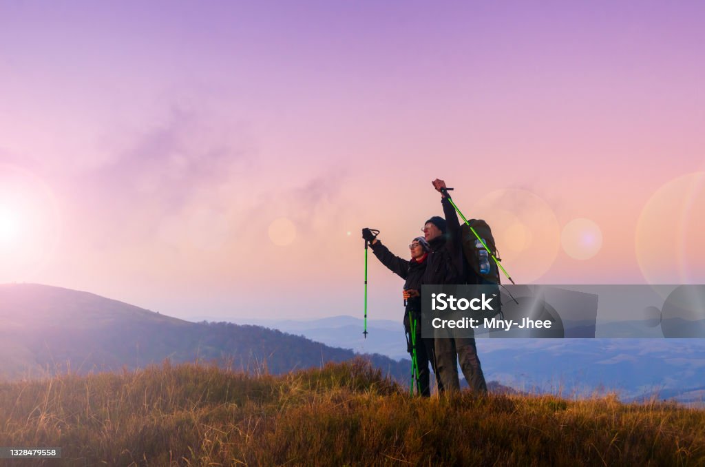 Hiker couple with backpacks meets sunset on the mountain top. Active lifestyle and wanderlust concept Hiking Stock Photo