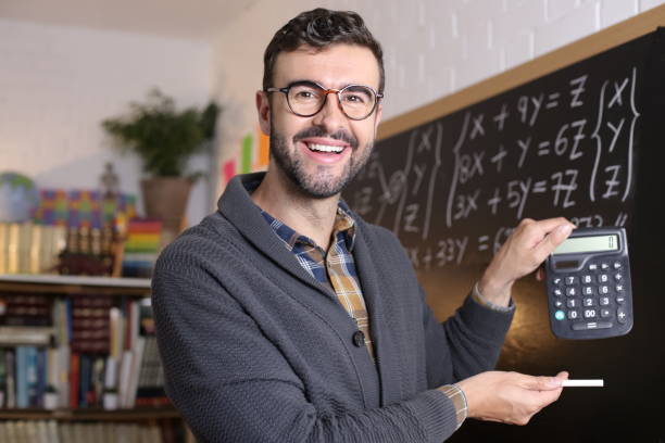 istock Math teacher holding a calculator in classroom 1328481834