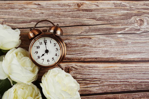 istock Alarm clock with White peony flowers border frame on wooden background 1328483413