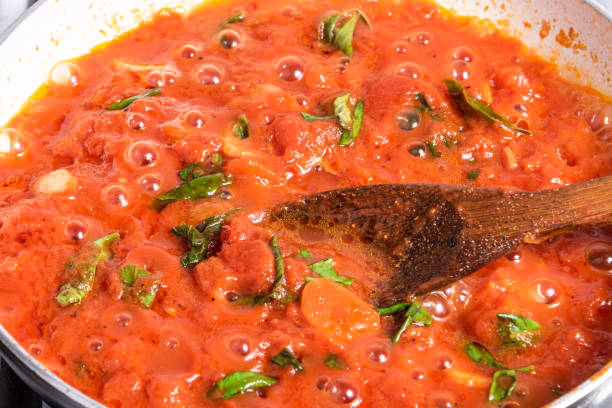 Cooking homemade italian tomato marinara sauce in a skillet close-up Cooking homemade italian tomato marinara sauce in a skillet close-up marinara stock pictures, royalty-free photos & images