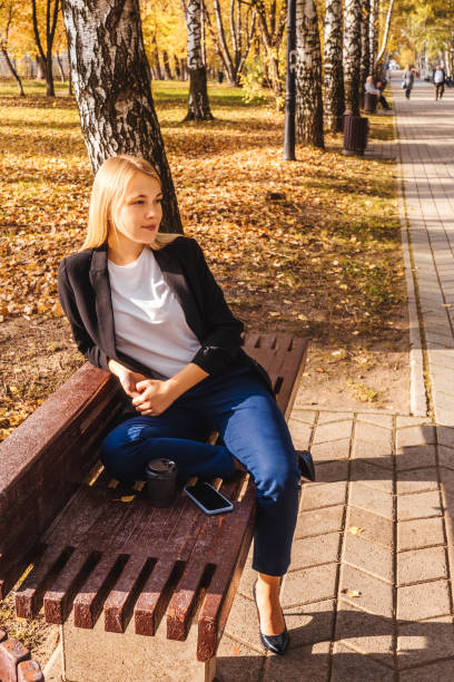 istock Woman sitting on bench in autumn park 1328487980
