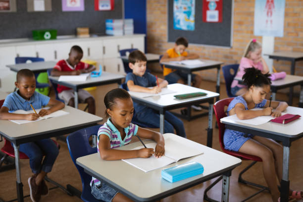 istock Group of diverse students studying while sitting on their desks in the class at school 1328488299