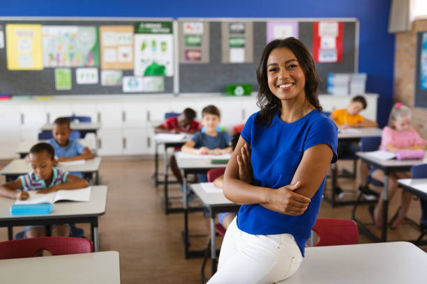 porträt einer afroamerikanischen lehrerin, die in der klasse der schule lächelt - teaching education teacher classroom stock-fotos und bilder