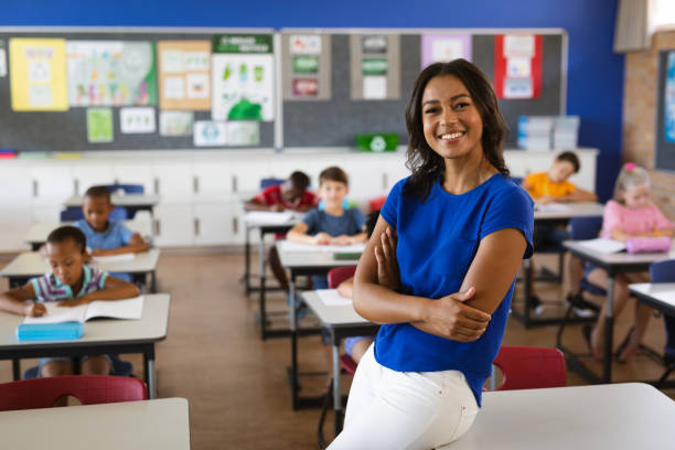 porträt einer afroamerikanischen lehrerin, die in der klasse der schule lächelt - lehrtaetigkeit stock-fotos und bilder