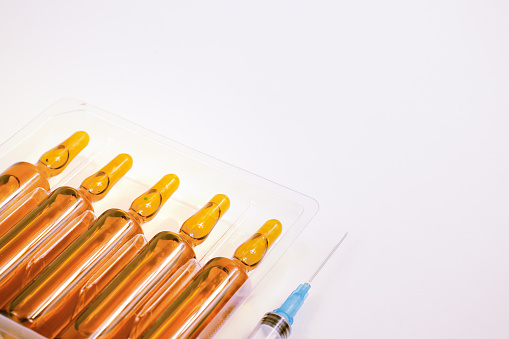 Medical ampoules in brown glass and syringe on a white background. Medicine and health concept.