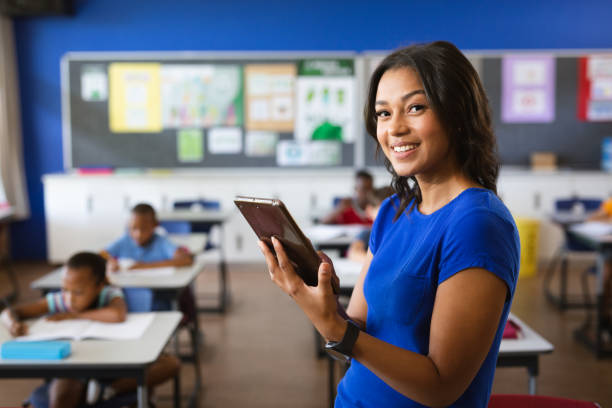 portrait d’une enseignante afro-américaine tenant une tablette numérique dans la classe à l’école - digital tablet student studying learning photos et images de collection