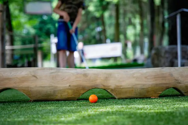 School kid boy playing mini golf with family. Happy child having fun with outdoor activity. Summer sport for children and adults, outdoors. Family vacations or resort