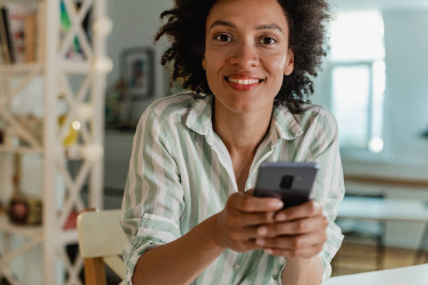 istock Beautiful woman is using mobile phone at home 1328491671
