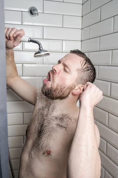 istock Funny man enthusiastically sings in the bathroom, using a shower with running water instead of a microphone. Lifestyle. 1328491909