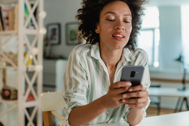 istock Beautiful woman is using mobile phone at home 1328491928