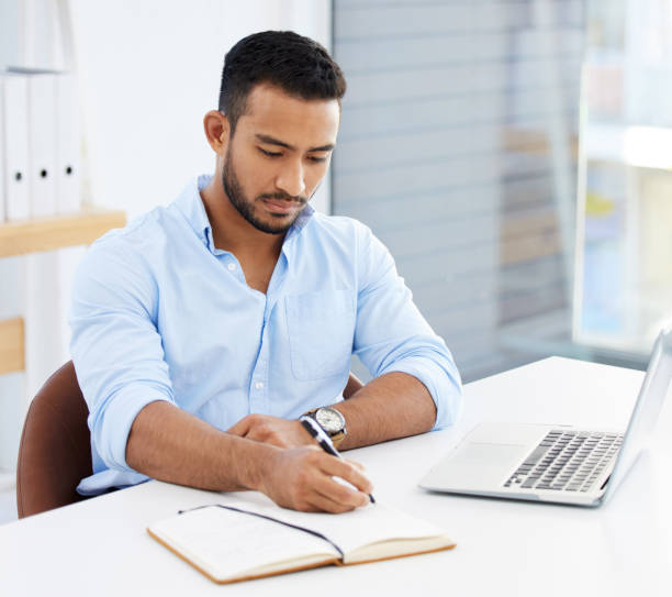 istock Shot of a young businessman writing in a notebook at work 1328492633