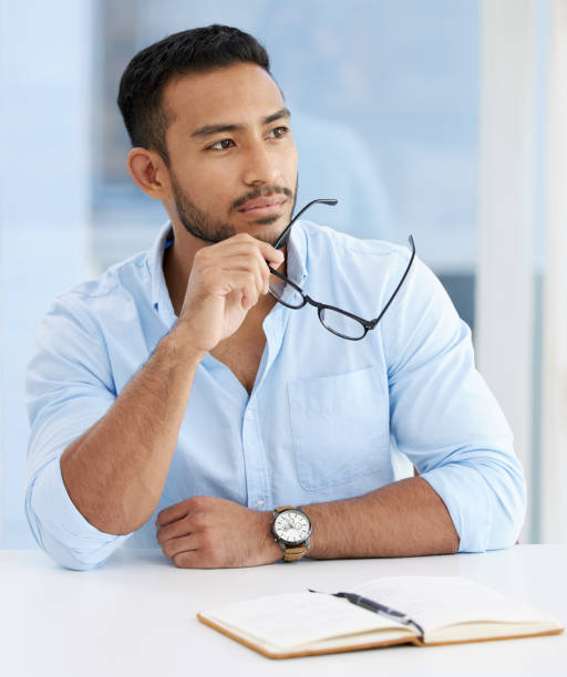 istock Shot of a young businessman writing in a notebook while using the phone at work 1328492646
