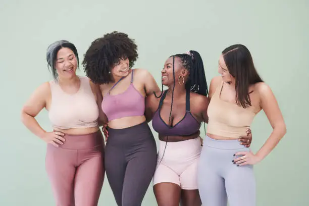 Photo of Studio shot of a group of women embracing each other against a green background