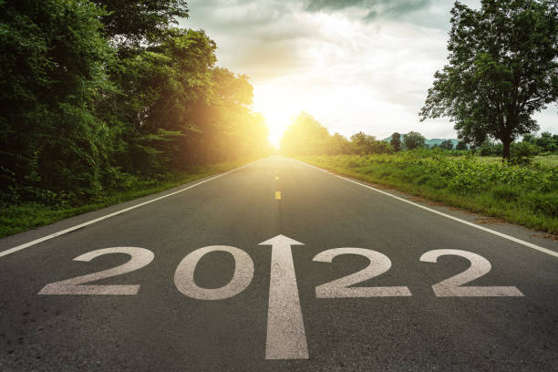 capodanno 2022 o concetto semplice. testo 2022 scritto sulla strada in mezzo alla strada asfaltata al tramonto. concetto di pianificazione e sfida, strategia aziendale, opportunità, speranza, nuovo cambiamento di vita - middle of the road immagine foto e immagini stock