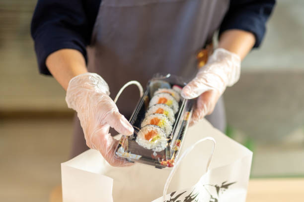 mano de una camarera llenando caja para llevar de sashimi y sushi, actividades alternativas de catering en tiempos de pandemia, entrega de comida asiática - sushi lifestyles japanese culture freshness fotografías e imágenes de stock