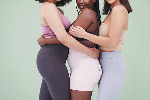 Toma de estudio recortada de un grupo de mujeres irreconocibles abrazándose unas a otras sobre un fondo verde photo