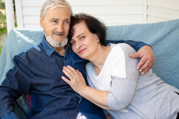 felice marito maturo e moglie anziana rilassante seduto sul divano sulla terrazza di casa, abbracciando e coccolando, sorridente coppia amorevole senior trascorrendo tenero fine settimana romantico insieme. mostrare affetto da cura - men latin american and hispanic ethnicity southern european descent mature adult foto e immagini stock