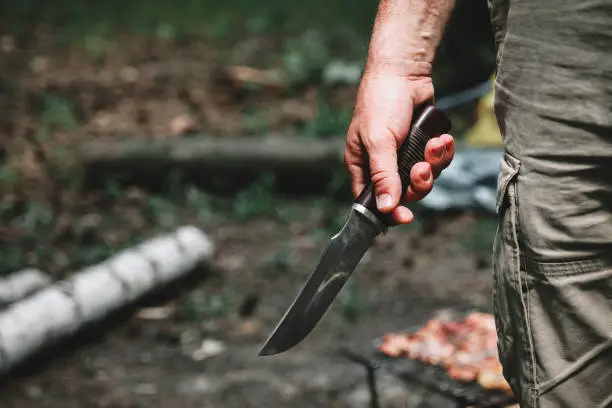 Photo of A man holding a large sharp knife in his hand