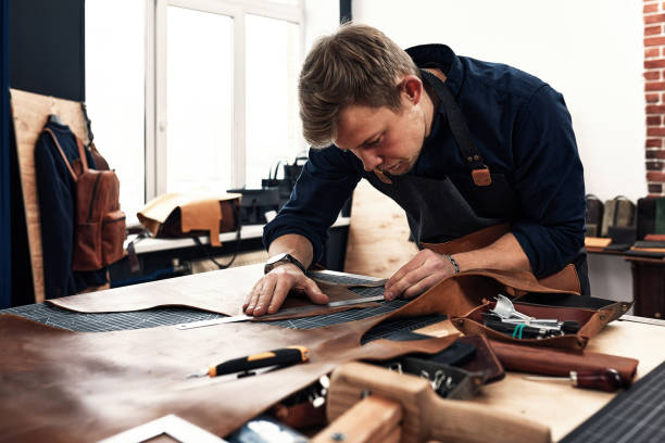 lederhandwerker, die in der werkstatt am tisch am tisch measupenets herstellen - schneiderberuf stock-fotos und bilder