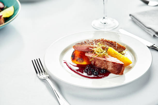 grilled duck breast with peaches in berry sauce, grilled duck fillet on a white plate, banquet serving of duck meat on a wedding table - peach nectarine fruit portion imagens e fotografias de stock