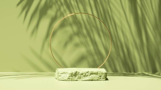 istock 3d render, abstract green background with tropical leaves shadow and bright sunlight. Minimal scene with cobblestone stage and golden round frame for organic cosmetic product presentation 1328499539