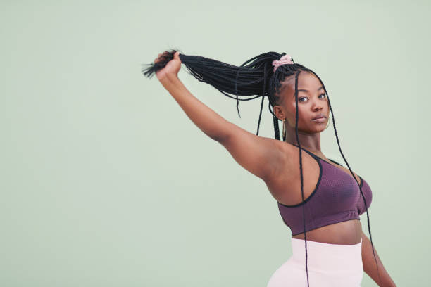 retrato de estudio recortado de una joven tirando de su cabello y posando sobre un fondo verde - cola de caballo fotografías e imágenes de stock