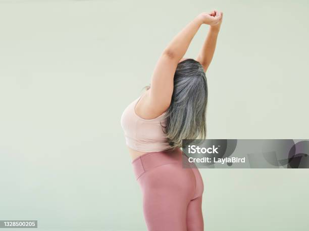 Rear Studio Shot Of An Unrecognizable Woman Stretching Against A Green Background Stock Photo - Download Image Now