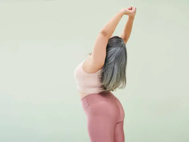 Photo of Rear studio shot of an unrecognizable woman stretching against a green background