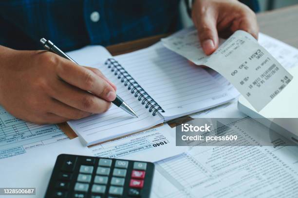 Man Using Calculate Domestic Bills On Wooden Desk In Office And Business Working Backgroundyoung Male Checking Balance And Costs With Us Irs 1040 Form Tax Statistics And Analytic Research Concepts Stock Photo - Download Image Now
