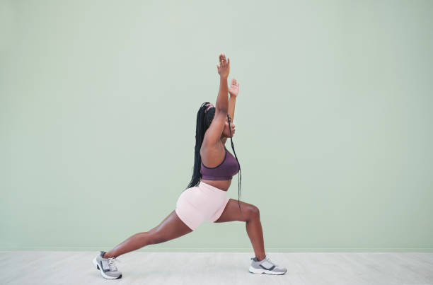 toma de estudio de cuerpo completo de una mujer joven haciendo ejercicio sobre un fondo verde - lunge fotografías e imágenes de stock