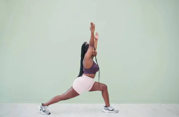 Photo of Full body studio shot of a young woman exercising against a green background