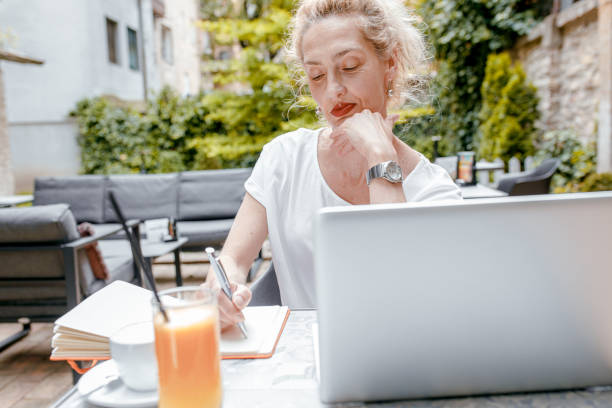 istock Smiling senior woman sitting in coffee shop using laptop. 1328501886